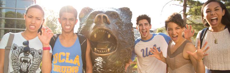 Students gather around bear statue.